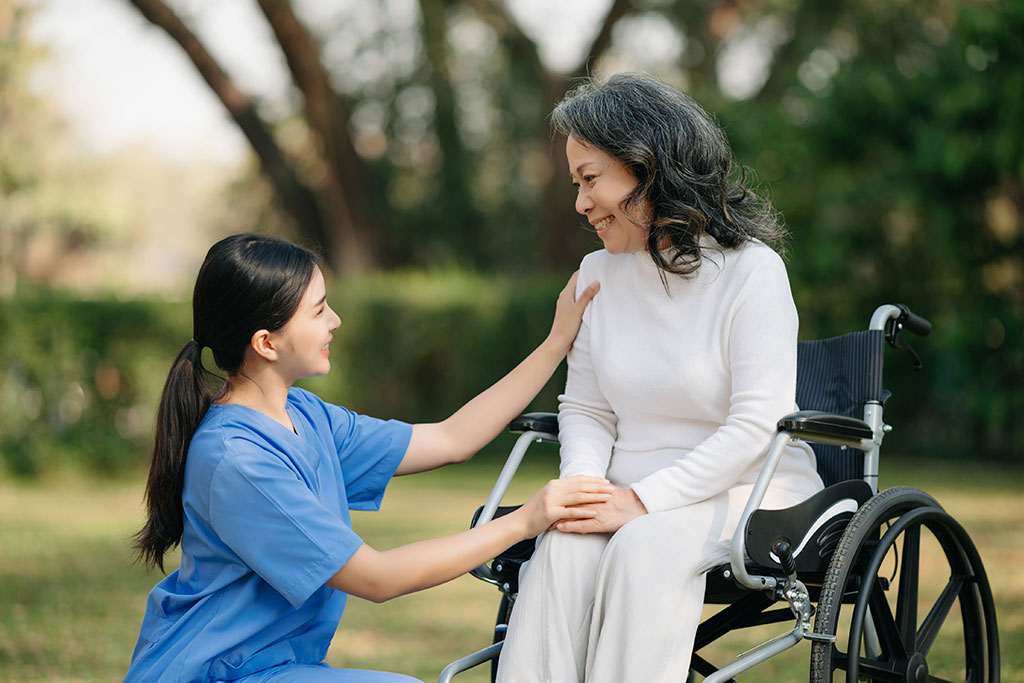 Elderly asian senior woman on wheelchair with Asian careful caregiver. Nursing home hospital garden concept.