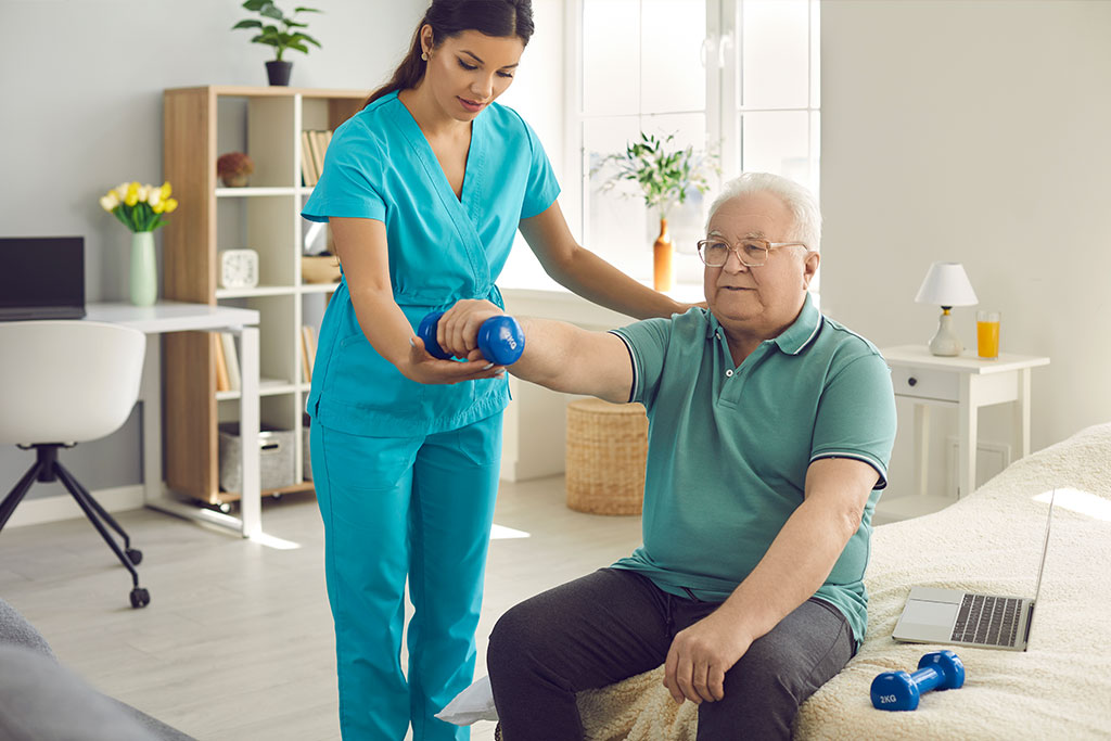 Physical therapist nurse helping patient to exercise with dumbbells at home