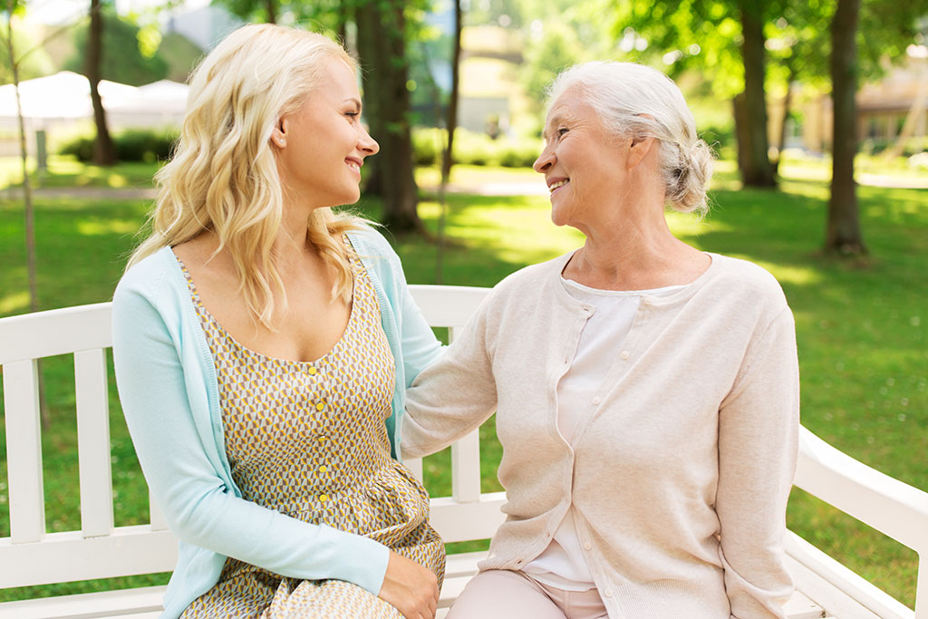 Daughter with senior mother hugging on park bench