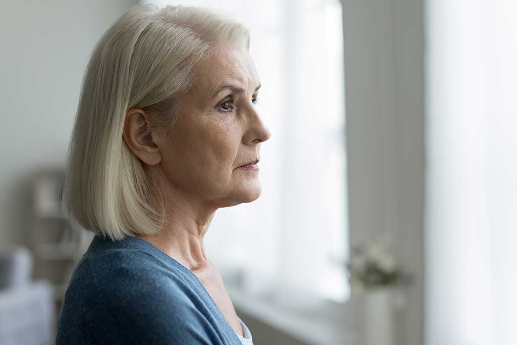 Close up portrait of serious upset older woman looking out window, lost in thoughts, think about problems, remember past, ponder future, feels depressed or lonely. Memories, melancholy, nostalgic mood